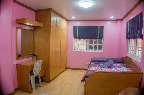 a bedroom with pink walls and a bed and a desk at Cozy Baguio House - Outlook Drive (DOT accredited) in Baguio