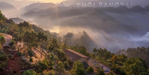 a misty valley with a house on a hill at Khói Panorama in Dồng Văn
