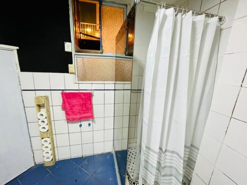 y baño con ducha y toalla rosa. en Valpro Hostal, en Valparaíso