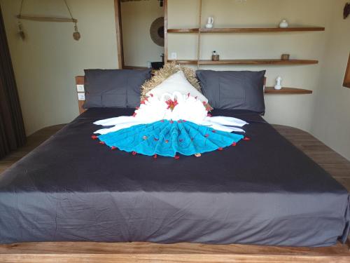 łóżko z niebieską kołdrą i biało-niebieską suknią w obiekcie Lodge tropical Fullmoon w mieście Uluwatu