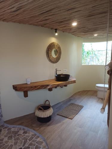 ein Bad mit einem Waschbecken und einem Wandspiegel in der Unterkunft Lodge tropical Fullmoon in Uluwatu