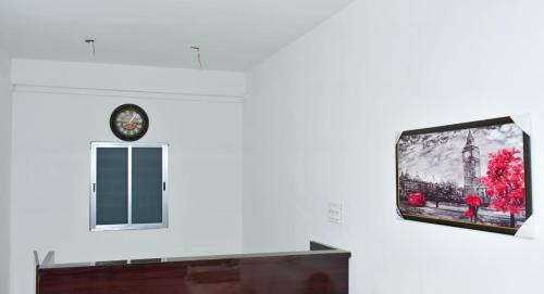 Elle comprend une télévision à écran plat murale avec une horloge. dans l'établissement DESIRE LODGE, à Dālkola