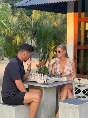 a man and woman sitting at a table playing chess at Moorea Boutique Resort Samui in Ban Tai