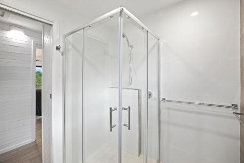 un baño blanco con cabina de ducha de cristal en The Stag, en Mylestom
