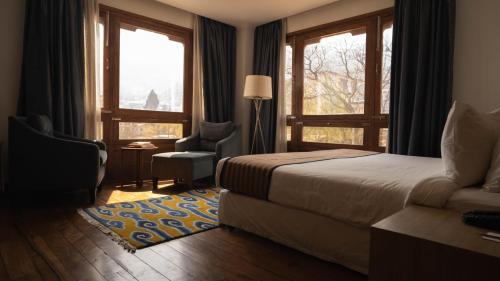 a bedroom with a bed and a chair and windows at Osel Thimphu Bhutan in Thimphu