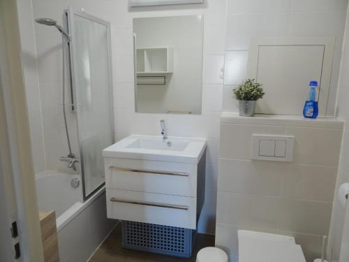y baño blanco con lavabo y ducha. en Wielingerbank E with a central location, en Nieuwpoort