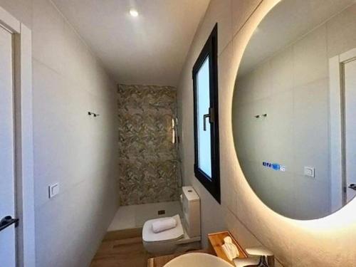 a bathroom with a round mirror and a toilet at Yellow Apartment in Puerto del Rosario in Puerto del Rosario