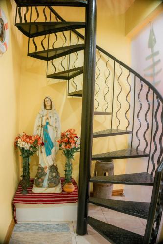 a statue of a nun next to a staircase with flowers at Cozy Baguio House - Outlook Drive (DOT accredited) in Baguio