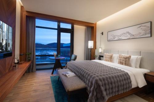 um quarto de hotel com uma cama grande e uma janela grande em Oakwood Suites Chongli em Chongli