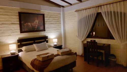a bedroom with a bed and a desk with a chair at Quinta Sierra de Fuego in Penipe