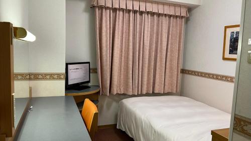 Zimmer mit einem Bett und einem Schreibtisch mit einem Computer in der Unterkunft Hotel Alpha-One Gotemba Inter in Gotemba
