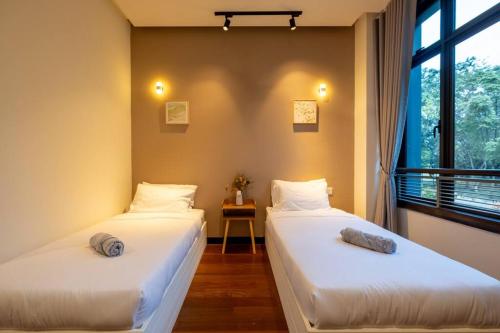 two beds in a room with a window at Bungalow Putrajaya 15pax w Private Pool Gathering in Putrajaya