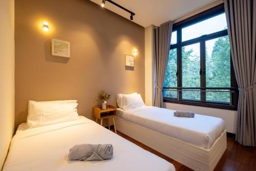 two beds in a room with a window at Bungalow Putrajaya 15pax w Private Pool Gathering in Putrajaya
