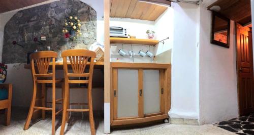 uma cozinha com um balcão e duas cadeiras de madeira em Casita la adornada em Taxco de Alarcón