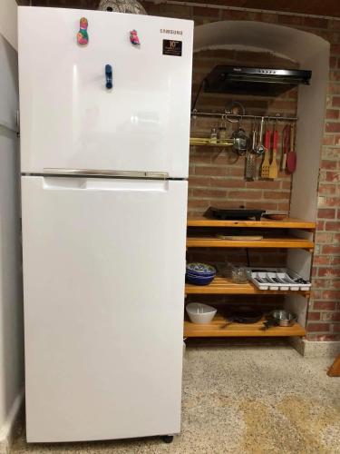 a white refrigerator in a kitchen next to a brick wall at La Adornada Orquidea in Taxco de Alarcón