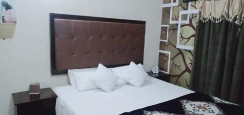 a bedroom with a bed with white sheets and pillows at Family Guest House Lahore Near Airport in Lahore