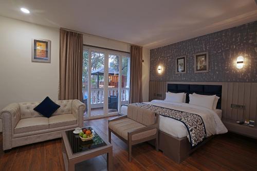 a hotel room with a bed and a couch at Grand Continent Anjuna A Sarovar Portico Affiliate Hotel in Anjuna