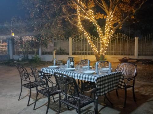 a table with chairs and lights in a yard at Sipanya Guesthouse in Muang Ph&ocirc;nsavan