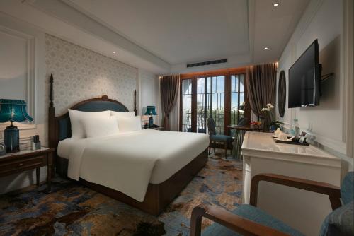 ハノイにあるThe Oriental Jade Hotelの大きなベッドとデスクが備わるホテルルームです。