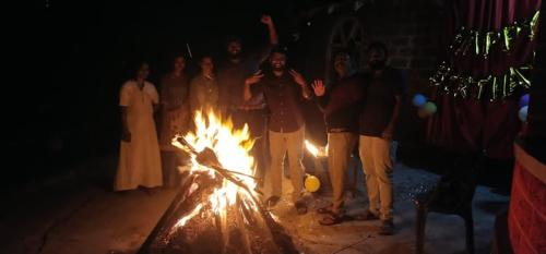 a group of people standing around a fire at Coorg Heritage Hill View Resort in Madikeri