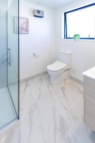 a bathroom with a toilet and a glass shower at Escape at the park: 1 bed 1 bath w/carpark in Christchurch