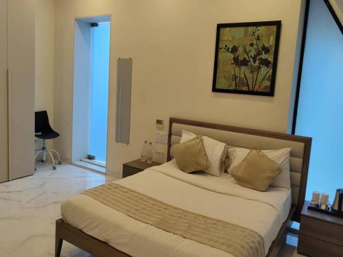 a bedroom with a bed and a painting on the wall at WOODS - Mangalyam Meadows in Valsad