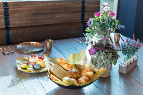 a table with two plates of bread and a vase of flowers at WOODS - Mangalyam Meadows in Valsad