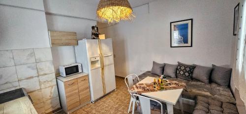 a kitchen with a couch and a table and a refrigerator at Pleasure Black Beach Perissa Santorini in Perissa