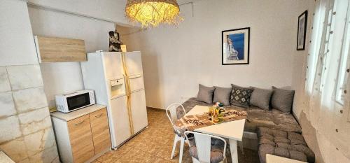 a living room with a couch and a table and a refrigerator at Pleasure Black Beach Perissa Santorini in Perissa