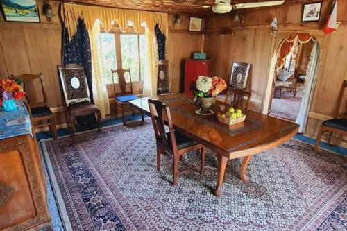 a dining room with a wooden table and chairs at Queens Lakehouse in Srinagar