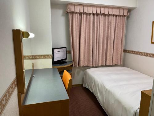 Habitación de hotel con cama y escritorio con ordenador en Hotel Alpha-One Gotemba Inter, en Gotemba