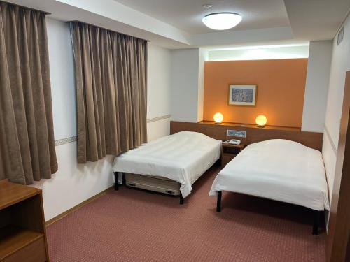 御殿場市にあるホテルアルファーワン御殿場インターのベッド2台と窓のある病室です。