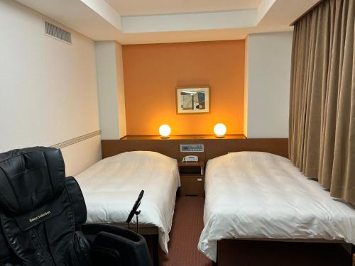 a hotel room with two beds and a chair at Hotel Alpha-One Gotemba Inter in Gotemba