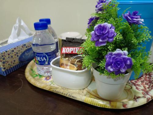 a tray with two flowers and a bottle of water at Alia Express Seri Ibai Permai in Kuala Terengganu