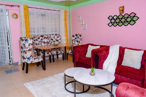 a living room with a red couch and a table at Ruby Modern Homes Nyeri-Skuta in Nyeri