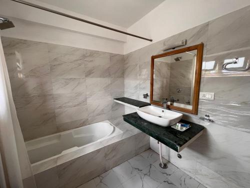 a bathroom with a sink and a tub and a mirror at Hotel New Glacier View in Leh