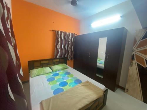 a bedroom with a bed and an orange wall at Samraj Stays in Coimbatore