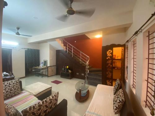 a living room with a couch and a staircase at Samraj Stays in Coimbatore
