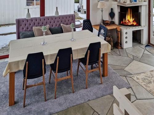 a dining room table with four chairs and a fireplace at Holiday home TJODALYNG 