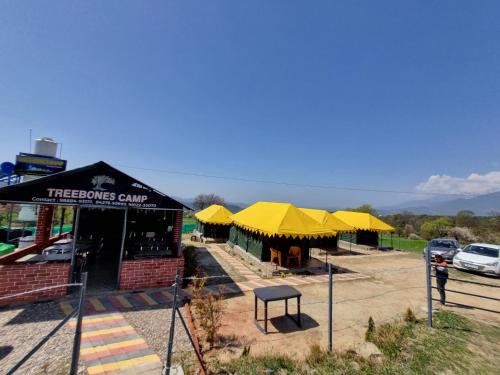 a store with yellow umbrellas in a parking lot at Tree Bones Camp in Bīr