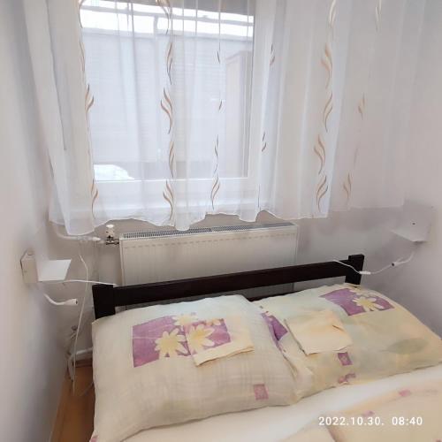 a bed with two pillows in front of a window at LBB apartman in Sátoraljaújhely