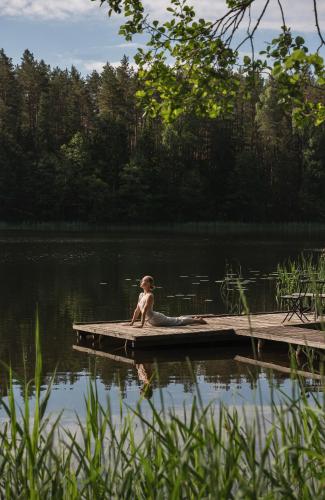 a young child sitting on a dock on a lake at Miškas Arjola in Kaltanėnai