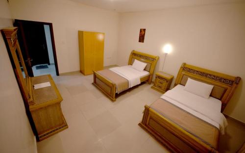a hotel room with two beds and a balcony at AL MARJAN FURNISHED APARTMENTS in Ajman 