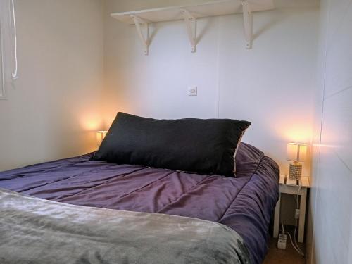 - un lit avec un oreiller noir dans l'établissement LE RHUYS, mobil home cosy proche des plages, à Sarzeau