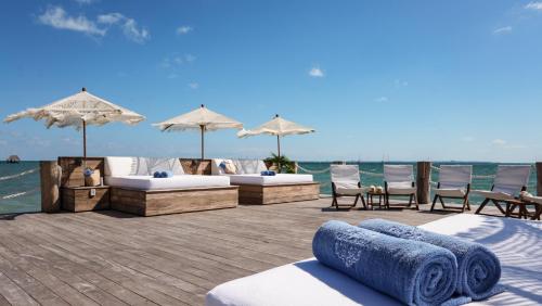 a deck with beds and umbrellas on the water at Villa Sha - Cancun Luxury Beachfront in Cancún