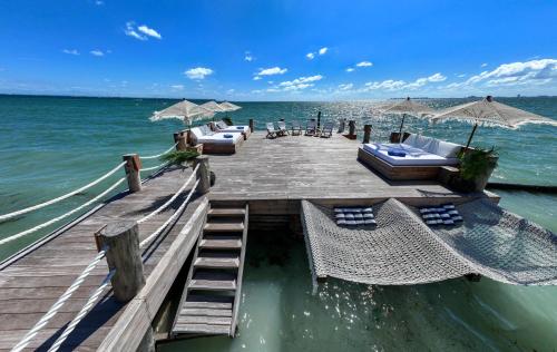 a wooden pier with chairs and umbrellas on the water at Villa Sha - Cancun Luxury Beachfront in Cancún