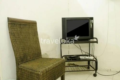 une télévision assise sur un support à côté d'une chaise dans l'établissement Rumah Kost 10 Gambir, à Jakarta