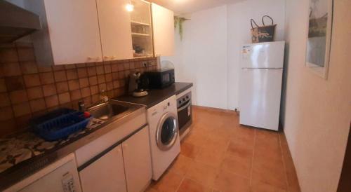 eine Küche mit einer Spüle und einem weißen Kühlschrank in der Unterkunft Le gîte du pavé in Saint-Paul
