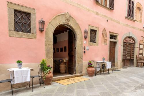 an entrance to a pink building with tables and chairs at LA FINESTRA SUL TRAMONTO Dimora Storica in Laterina