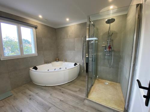 La grande salle de bains est pourvue d'une baignoire et d'une douche en verre. dans l'établissement Villa entre mer et golf, à Saint-Raphaël